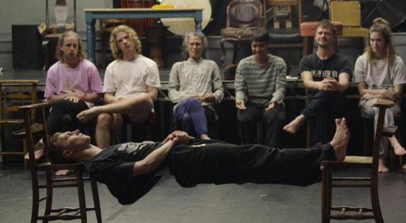 6 people looking at a person stretched out between two chairs